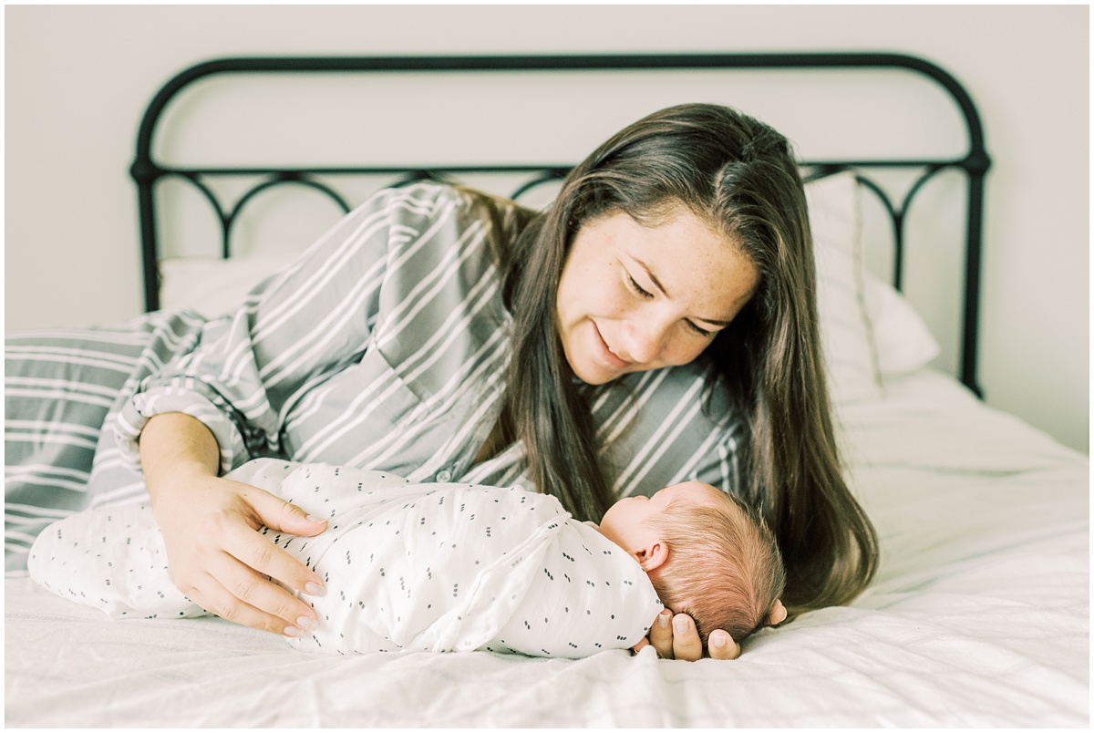 Greenville newborn photographer, mom and baby cuddling on bed